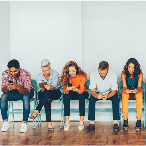Variety of people looking at different media including books, mobile phones and tablets.
